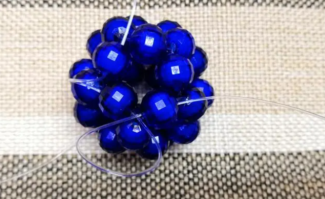 第十四步：右手線穿上兩顆珠子，并回穿與左線打結，形成如圖15的樣子