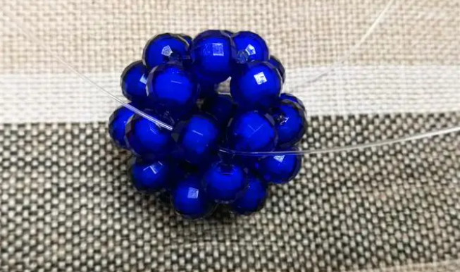 第十四步：右手線穿上兩顆珠子，并回穿與左線打結，形成如圖15的樣子